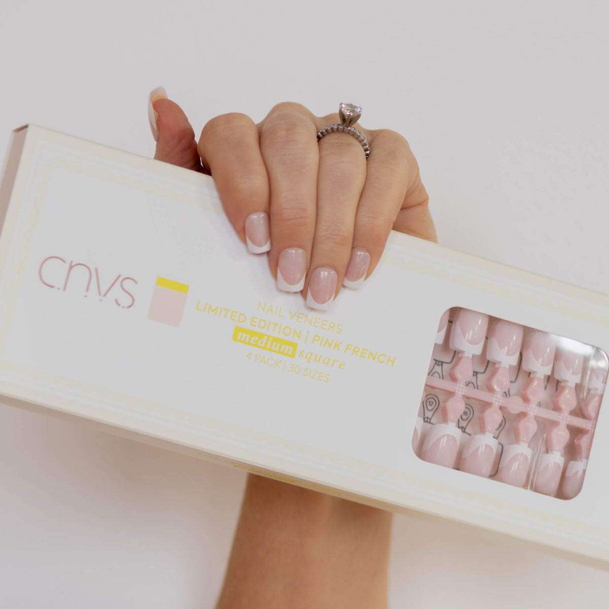 Hand holding a box with CNVS Nails branding against a light background CNVS Medium Pink French Nails