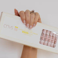 Hand holding a box with CNVS Nails branding against a light background CNVS Medium Pink French Nails