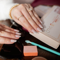CNVS Nails Medium Pink French Almond nail on hand reaching into purse for nail box and accessories
