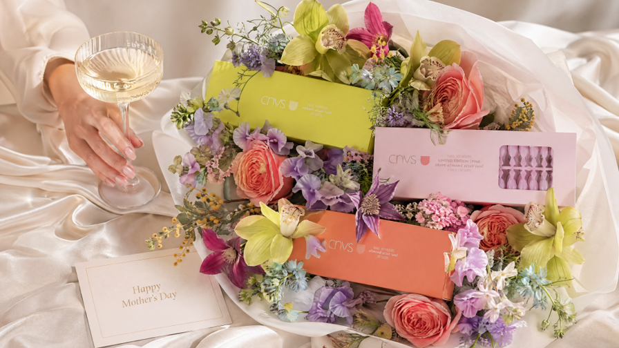 Floral arrangement with a glass of champagne and a card on a white surface