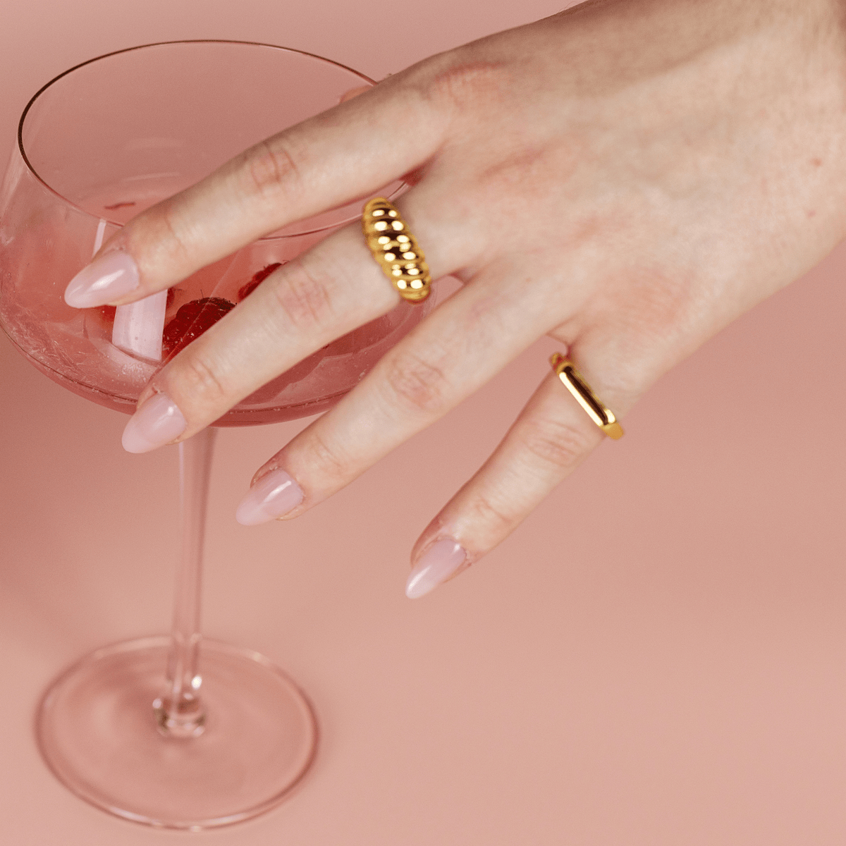 Limited Edition Pink Medium Almond Nails by CNVS Nails on a woman's hand that reaches for a cocktail 